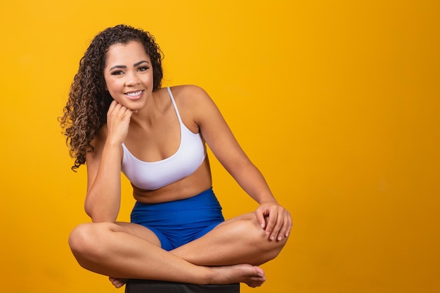 Piękna młoda kobieta afro w stroju fitness uśmiechając się patrząc na kamery z miejsca na tekst. Poziomy