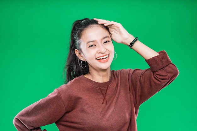 Piękna młoda kobieta Azji uśmiechając się trzymając nad głową na białym tle na zielonym tle