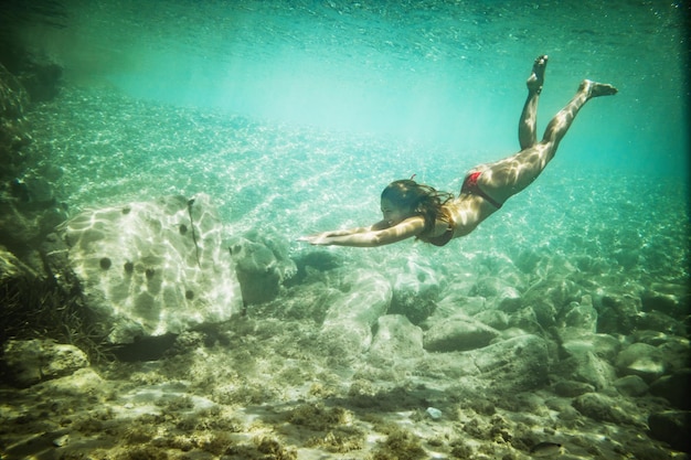 Piękna młoda kobieta bawi się podczas letnich wakacji zwiedzając dno morskie podczas nurkowania w morzu.