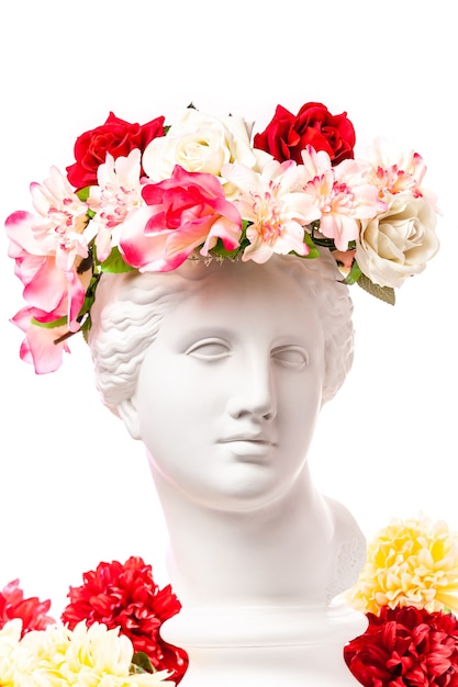 Piękna młoda kobieta biała twarz i kolorowe kwiaty. Gipsowe antyczne popiersie Wenus w kwiatowy wieniec. Piękna wiosna i lato model dziewczyna z bukietem świeżych.