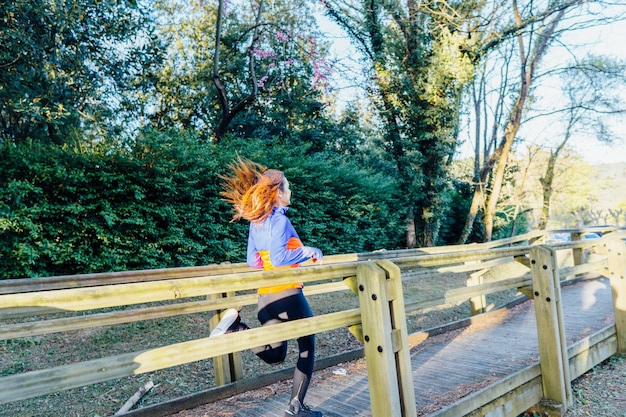 Piękna Młoda Kobieta Biegnąca Przez Park Wiosną Lub Latem W Lesie Jest W Dół Chodnika Od Tyłu. Koncepcja Samoopieki Sportowej