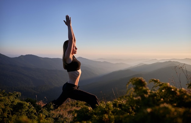 Piękna młoda kobieta ćwiczy jogę w górach