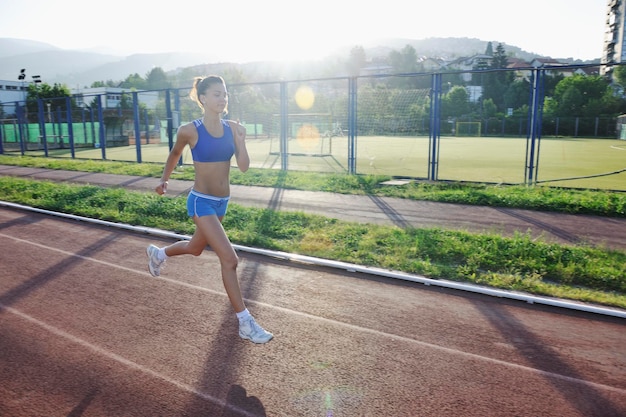 piękna młoda kobieta ćwiczy jogging i bieganie na torze lekkoatletycznym na stadionie o wschodzie słońca