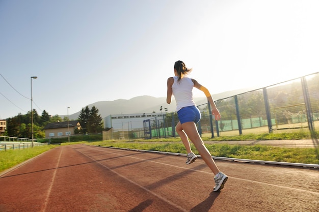 piękna młoda kobieta ćwiczy jogging i bieganie na torze lekkoatletycznym na stadionie o wschodzie słońca