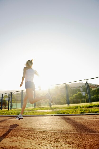 piękna młoda kobieta ćwiczy jogging i bieganie na torze lekkoatletycznym na stadionie o wschodzie słońca