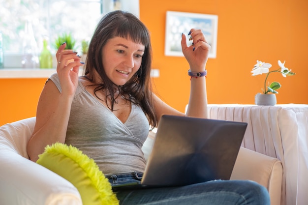 Piękna młoda kobieta emocjonalnie patrząc na laptopa. Emocjonalne zaskoczenie i płacz o sukces.