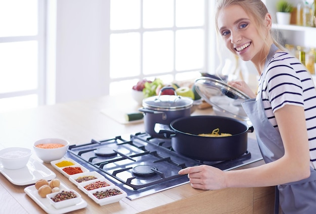 Zdjęcie piękna młoda kobieta gotuje w kuchni w domu