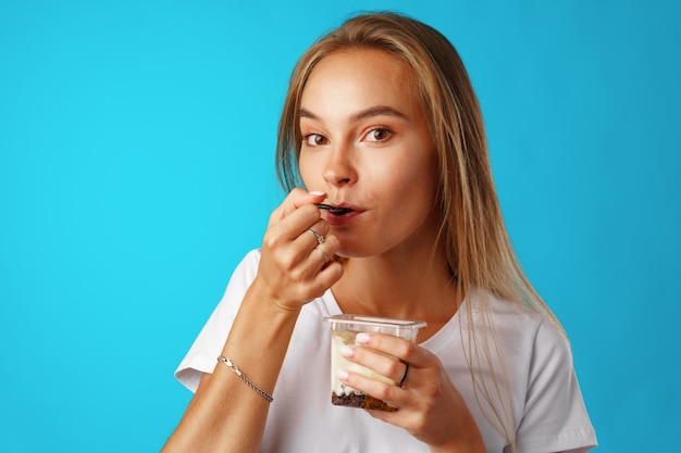 Piękna młoda kobieta jedzenie jogurtu z łyżką