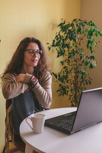 Zdjęcie piękna młoda kobieta jest ubranym szkła i przypadkowych ubrania używać laptop