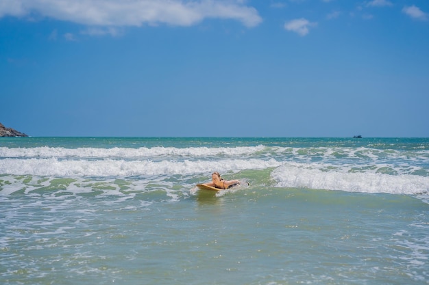 Piękna młoda kobieta jeździć na fali sportowiec surfer kobieta surfing na tle błękitnego nieba chmury i