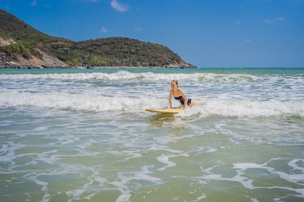 Piękna młoda kobieta jeździć na fali sportowiec surfer kobieta surfing na tle błękitnego nieba chmury i