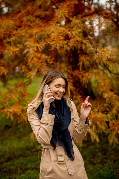 Piękna młoda kobieta korzystająca z telefonu komórkowego w jesiennym parku