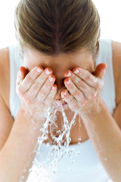 Zdjęcie piękna młoda kobieta myje jej twarzy chełbotania wodę w domowej łazience.