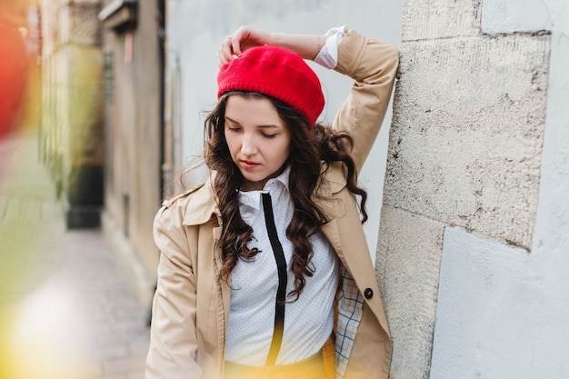 Piękna Młoda Kobieta Na Ulicy Miasta. Dziewczyna Szczęśliwy Turysta Spacery Na świeżym Powietrzu. Wiosna Moda Portret ładna Brunetka Kobieta Pozowanie Na Starym Mieście. Rozmyte Kwiaty Na Pierwszym Planie