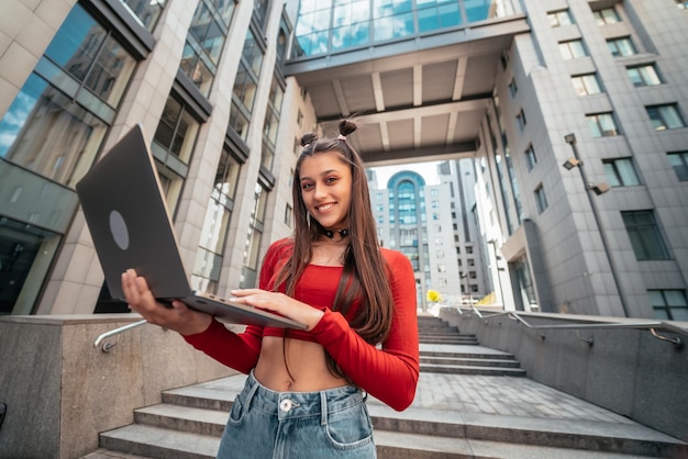 Piękna młoda kobieta na ulicy za pomocą laptopa