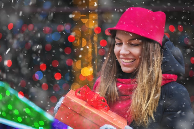 Zdjęcie piękna młoda kobieta odbiera prezent na ulicy przed ozdobioną gablotą
