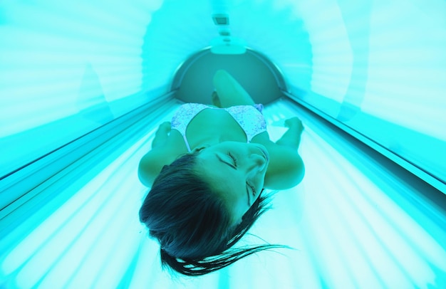 Zdjęcie piękna młoda kobieta opalająca się w solarium