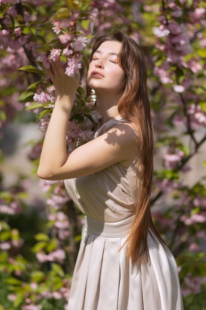 Piękna młoda kobieta pozowanie w kwitnącym ogrodzie sakura.