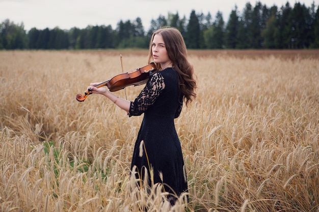 Piękna młoda kobieta przestała grać na skrzypcach i odwraca wzrok