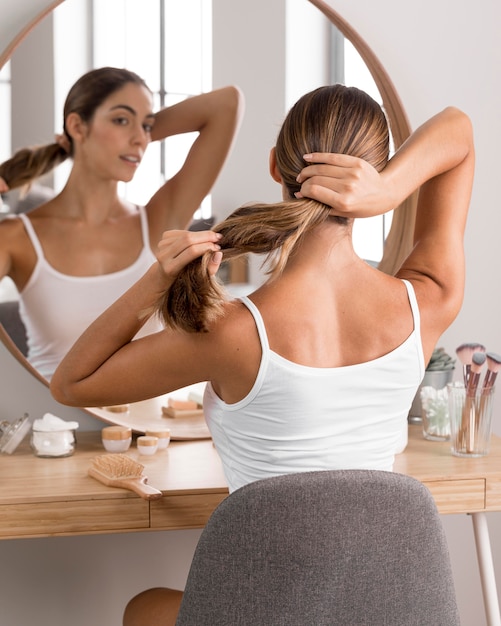 Zdjęcie piękna młoda kobieta przy użyciu produktów i patrząc w lustro