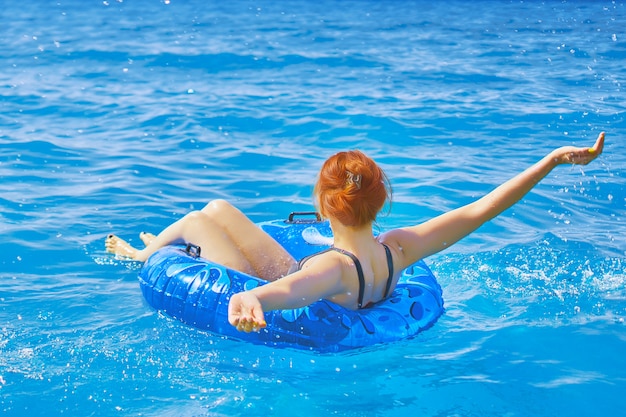 Piękna młoda kobieta relaksuje na nadmuchiwanym pierścionku w wodzie morskiej