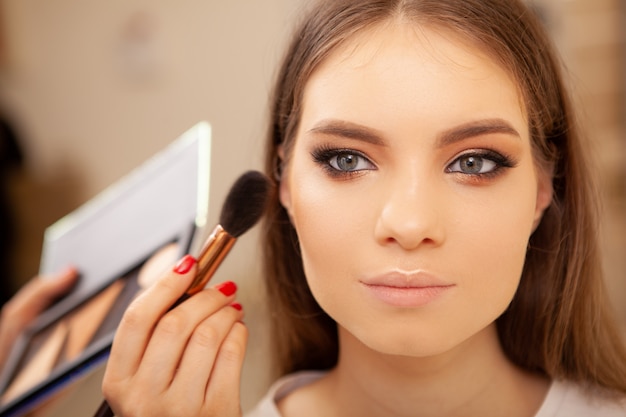 Zdjęcie piękna młoda kobieta robi fachowemu makijażowi robić