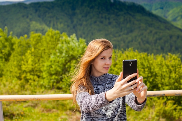 Piękna młoda kobieta robi selfie na tle zielonej przyrody