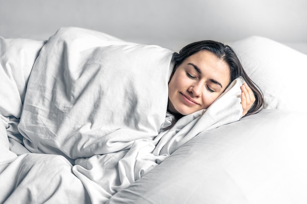 Piękna młoda kobieta śpi w białym łóżku