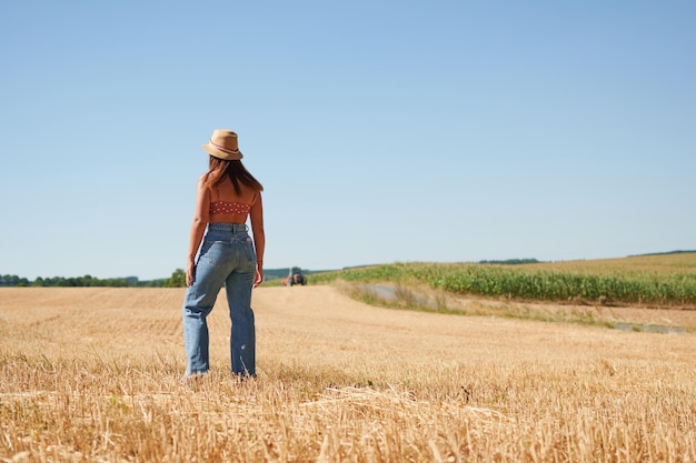Piękna młoda kobieta stojąca w polu pszenicy w słoneczny dzień na wsi