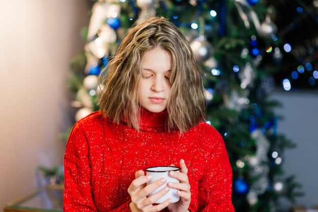 Piękna młoda kobieta świętująca Boże Narodzenie w domu, bawiąca się podczas otwierania prezentów