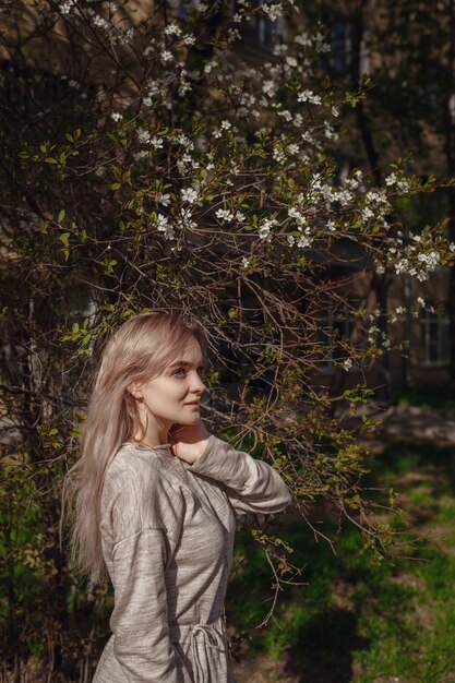 Piękna młoda kobieta w beżowej sukience z dzianiny spaceruje ulicami Moskwy, słoneczna wiosenna pogoda