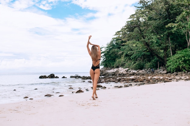 Piękna młoda kobieta w czarnym bikini, odpoczynek na plaży