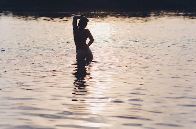 Piękna młoda kobieta w czerwonym stroju kąpielowym pozuje blisko rzeki Lato styl życia