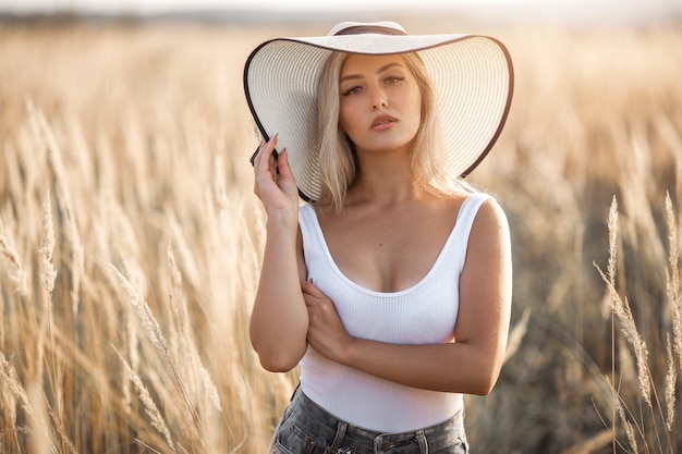 Piękna młoda kobieta w kapeluszu w letnim polu