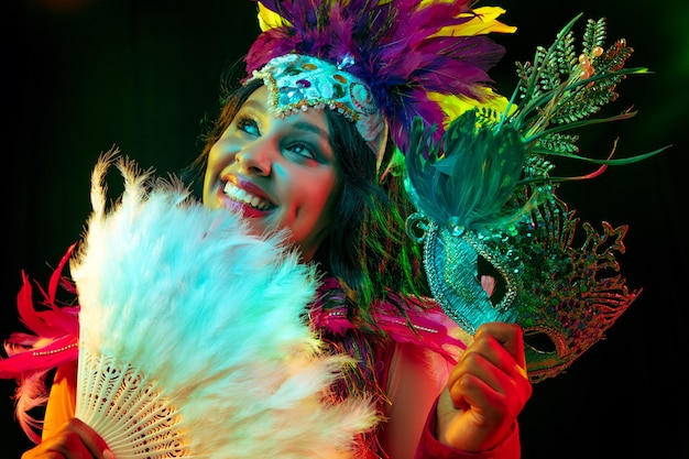 Piękna młoda kobieta w karnawałowej masce i kostiumie maskaradowym w kolorowe światła