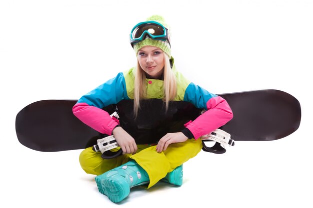 Piękna młoda kobieta w kombinezonie narciarskim i okularach narciarskich siedzieć z sbowboard