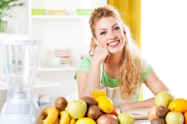 Piękna młoda kobieta w kuchni z owocami. Patrząc na aparat.
