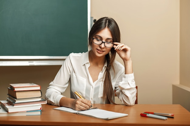 Piękna młoda kobieta w okularach na studia na uniwersytecie, czytanie książek
