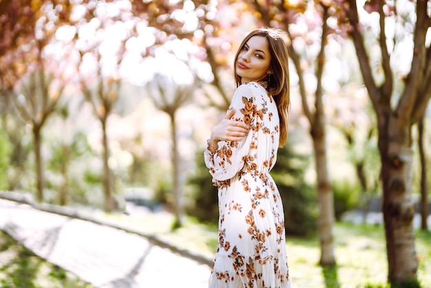 Zdjęcie piękna młoda kobieta w pobliżu kwitnącego drzewa wiosennego atrakcyjna dziewczyna cieszy się czasem na zewnątrz w parku