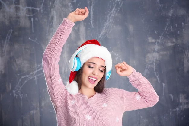 Piękna młoda kobieta w Santa hat słucha muzyki świątecznej na tle grunge