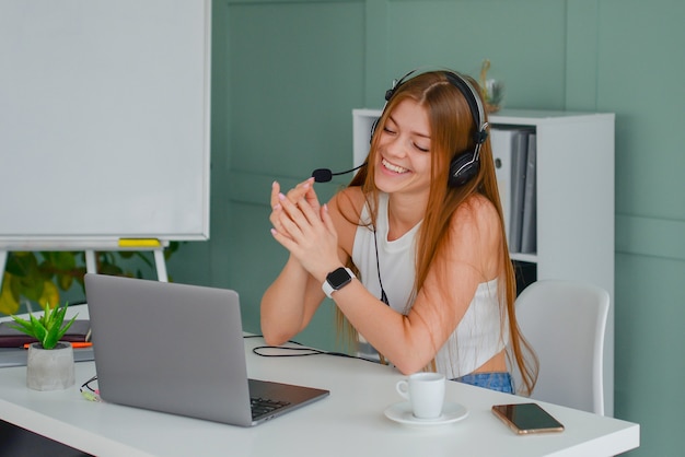 piękna młoda kobieta w zestawie słuchawkowym komunikuje się online z laptopem w biurowym stylu życia f