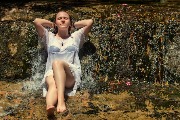 Piękna młoda kobieta z białą sukienką w pobliżu strumienia wody wodospad.