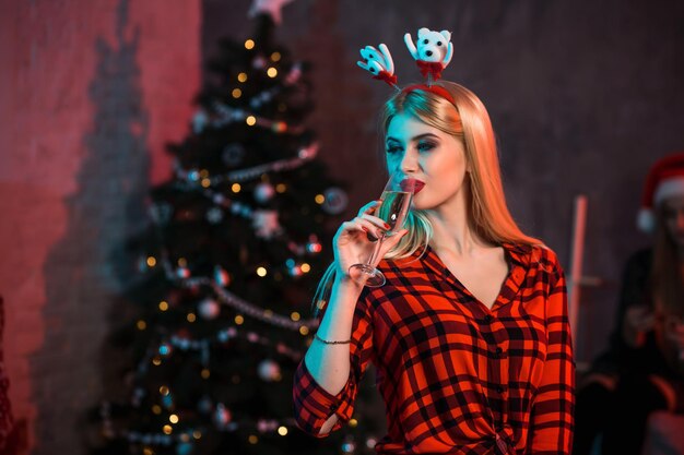 Piękna młoda kobieta z lampką szampana na przyjęciu bożonarodzeniowym