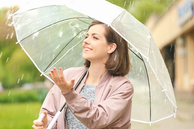 Piękna młoda kobieta z parasolem na zewnątrz w deszczowy dzień