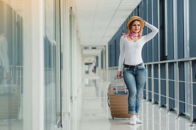 Piękna młoda kobieta z walizką na lotnisku