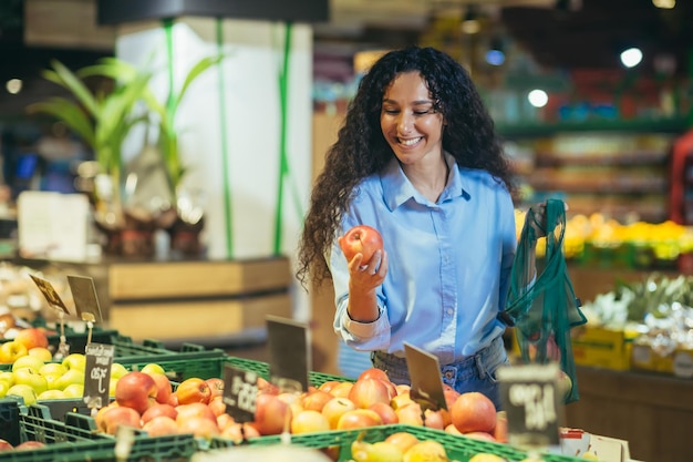 Piękna młoda latynoska robi zakupy w supermarkecie, uśmiecha się do warzyw