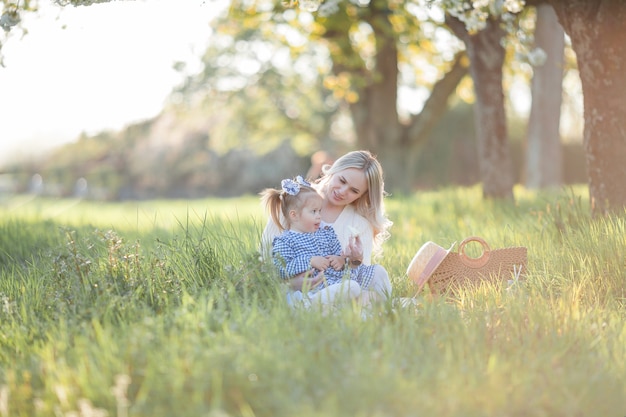 Piękna Młoda Mama Z Córeczką Odpoczywa Na Pikniku W Kwitnącym Ogrodzie