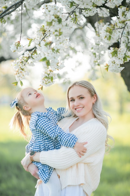 Piękna młoda mama z córeczką odpoczywa na pikniku w kwitnącym ogrodzie