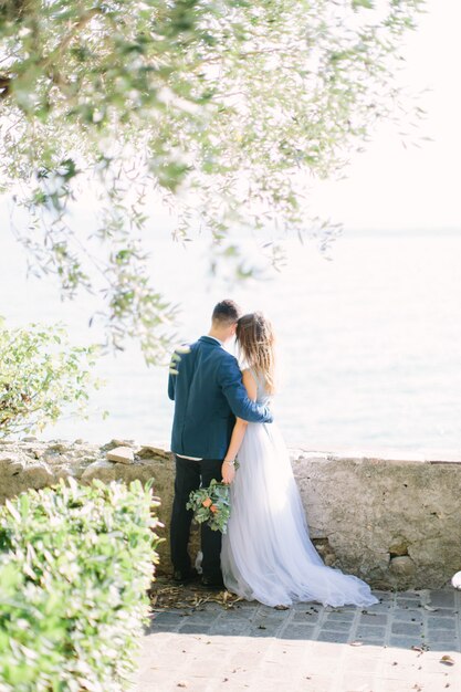 Piękna młoda para, obejmując i spacery w ogrodzie zamku Scaliger na tle jeziora Garda. Sirmione, Włochy