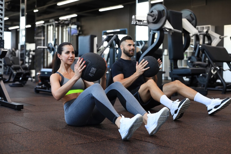 Zdjęcie piękna młoda para sportowa pracuje z piłką lekarską w siłowni.